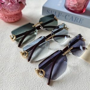 Detail of rimless sunglasses featuring gradient lenses and gold hollowed metal hinges