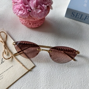 Détail de lunettes de soleil œil-de-chat sans monture avec verres roses dégradés