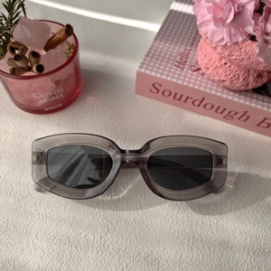 Gros plan de lunettes de soleil ovales rétro avec monture grise translucide sur table