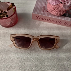 Détail de lunettes de soleil rectangulaires vintage en résine ambre sur tissu blanc