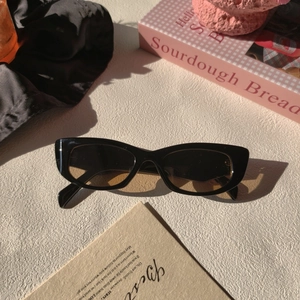 Détail de lunettes de soleil œil-de-chat vintage avec monture noire et verres ambrés polis