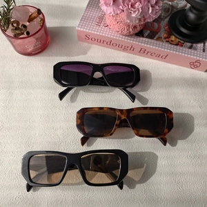 Three pairs of vintage rectangle sunglasses with thick frames on a decorative tabletop