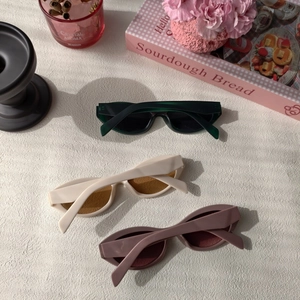 Close-up of three cat-eye resin sunglasses in olive, cream, and dusty rose hues