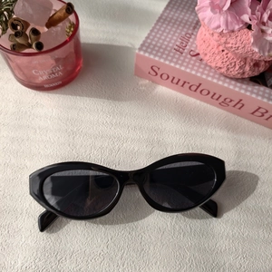 Chic black cat eye sunglasses on a cream textured surface with stylish lifestyle props
