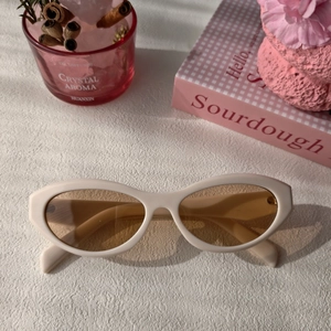 Detail of retro cat-eye sunglasses with cream resin frame and light brown lenses