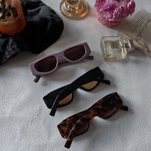 Three retro rectangle sunglasses in matte purple, black, and tortoise frames on silk background