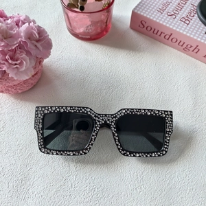 Gros plan de lunettes de soleil carrées noires avec strass sertis main et verres foncés