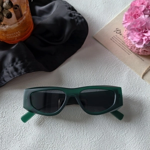 Flat lay of retro dark green rectangular sunglasses with black lenses and chic props