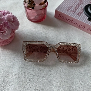 Détail de lunettes de soleil carrées oversize avec monture sertie de cristaux roses