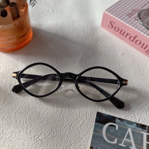 Close-up of black retro frame glasses with gold metal accents on stone background