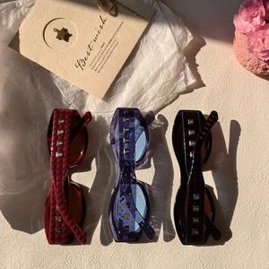 Detail of vintage square sunglasses with quilted temple design and metal rivets in three colors