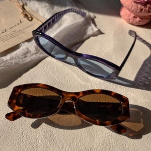 Artistic layout of retro rectangular purple and tortoiseshell sunglasses on a white paper