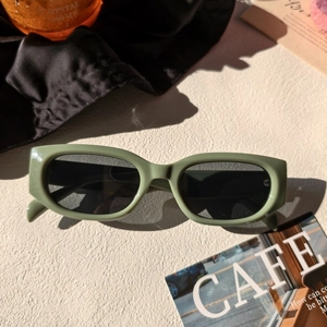 Détail de lunettes de soleil rectangulaires vert avocat sur une surface texturée élégante