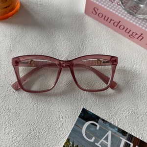 Gros plan sur la monture translucide rose-violet avec détails métalliques en U dorés élégants
