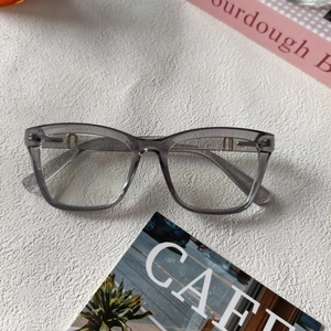 Détail des lunettes en résine gris-violet avec charnières dorées élégantes en forme de H