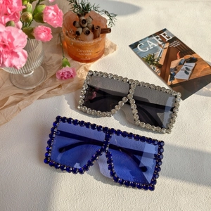 Detail of oversized square sunglasses with luxury rhinestone encrusted frames on a desk