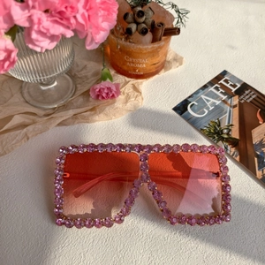 Close-up of pink rhinestone square sunglasses with gradient lenses and carnation props