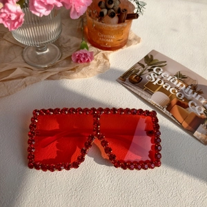 Detail of red oversized square sunglasses with sparkling rhinestones and red lenses