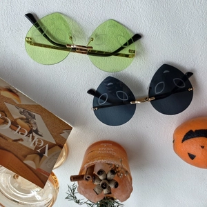 Detail of alien-shaped rimless party glasses with gold temples and green lenses