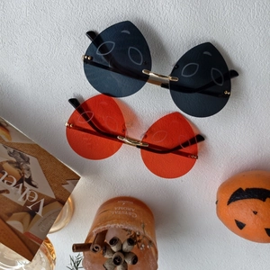 Detail of rimless Halloween ghost sunglasses in orange and black for party decor