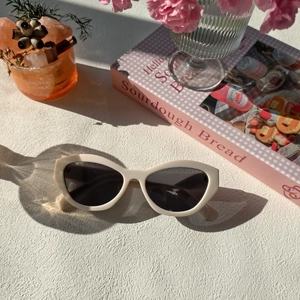 Lunettes de soleil œil de chat crème chic sur surface texturée avec éclairage doux