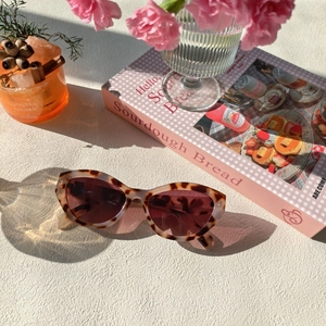 Détail de lunettes de soleil œil de chat écaillées avec verres foncés sur surface beige