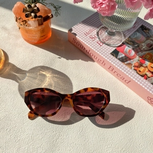 Détail de lunettes de soleil œil de chat écaille sur surface blanche avec ombres portées