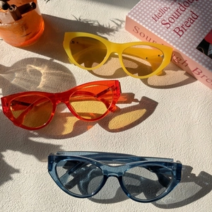 Three pairs of vintage cat-eye sunglasses in yellow, orange, and blue translucent frames