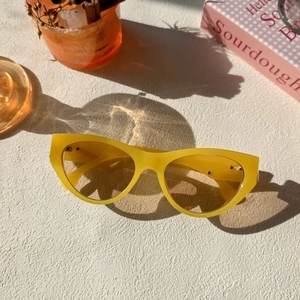 Flat lay of retro yellow cat-eye sunglasses with transparent lenses and summer props