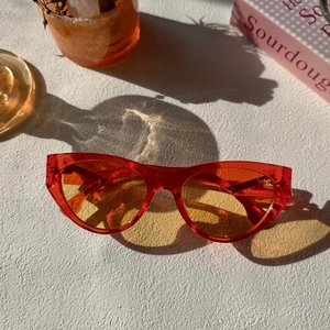 Artistic macro shot of red cat eye sunglasses with yellow lenses on a textured surface