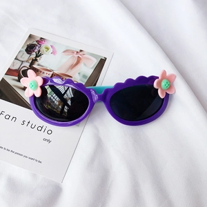 Detail der lila Kinder-Blumen-Sonnenbrille mit gewelltem Rahmen und blauen Bügeln