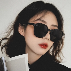 Close-up of a stylish woman wearing black oversized square sunglasses with dark lenses