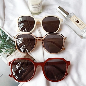 Retro oversized resin sunglasses in cream, tea, and red colors on a stylish background