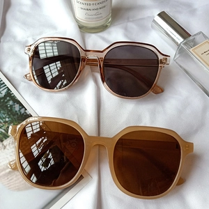 Flat lay of retro oversized sunglasses in brown and tortoiseshell on a white fabric surface
