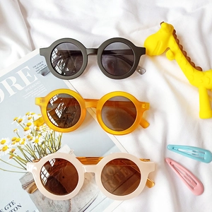 Vue à plat de lunettes de soleil rondes pour enfants en noir, ambre et blanc crème