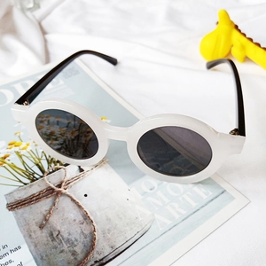 Détail de lunettes de soleil rondes pour enfants en plastique blanc et verres foncés