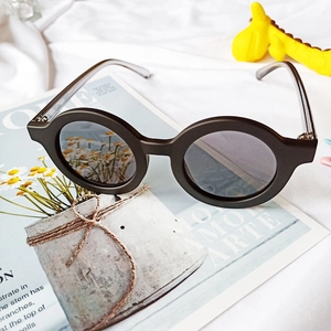 Détail de lunettes de soleil rondes noir mat pour enfants sur un magazine avec girafe