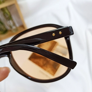 Detail of black sunglasses frame with gold star rivets and orange tinted lenses
