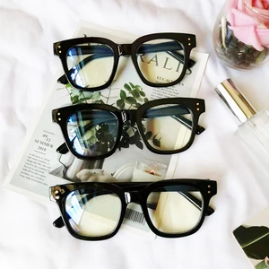 Trois lunettes tendance à monture noire épaisse anti-lumière bleue sur un tissu blanc