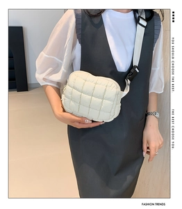 Detail of white quilted puffy crossbody bag with adjustable wide strap on Asian model