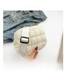 Detail shot of white quilted puffy crossbody bag with textured fabric and wide strap