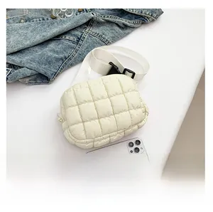 Detailed size comparison of the white quilted puffer bag next to a smartphone