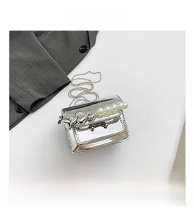 Detail of silver patent leather mini bag with pearl heart handle and ball chain strap