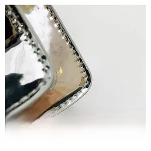Detailed close-up of glossy silver mirror fabric and metallic chain stitching on mini bag