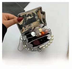 Silver mirror mini bag with pearl handle showing dual compartments for cosmetics