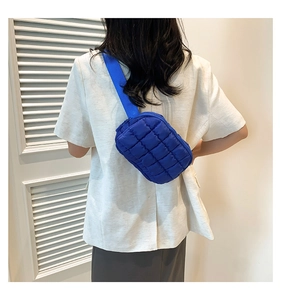 Detail of blue quilted puffer crossbody bag with adjustable wide nylon shoulder strap