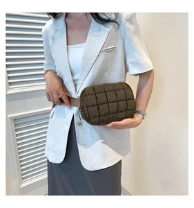 Detail of dark brown quilted crossbody bag featuring padded fabric and zipper closure