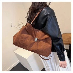 Detail view of large brown suede shoulder bag featuring a polished silver metal buckle lock