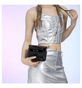 Close-up of black patent leather mini bag with decorative pearl and silver chain strap