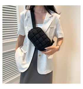 Detail of black quilted crossbody bag showing soft nylon texture and metallic zipper finish